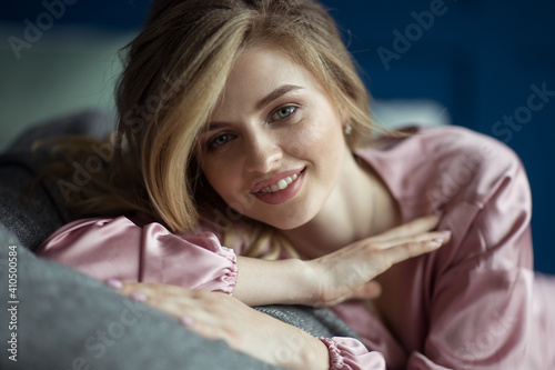 Fotografia Close-up portrait of young beautiful blonde woman with wavy hair in a pink peignoir with a plunging neckline