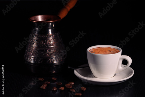 Obraz na płótnie White cup of coffee, copper cezve and coffee beans on black wooden table. Low key. Copy space. w salonie