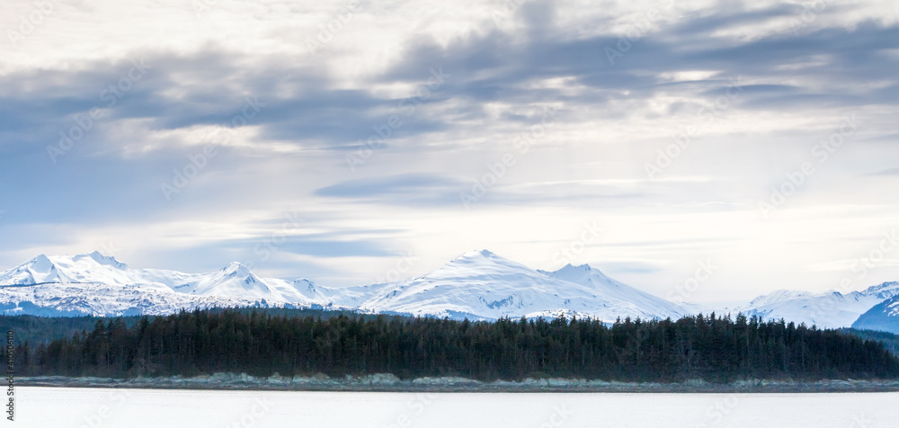 Panoramic view of snow-capped mountains and evergreen trees along the coast of southern Alaska