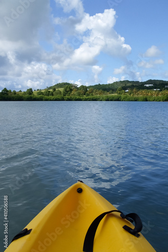 isolated yellow kayak on calm waters with trees and mountains and clouds in background as concept for solitude, adventure, exploring, calm, distance, and peaceful state of mind © Gina