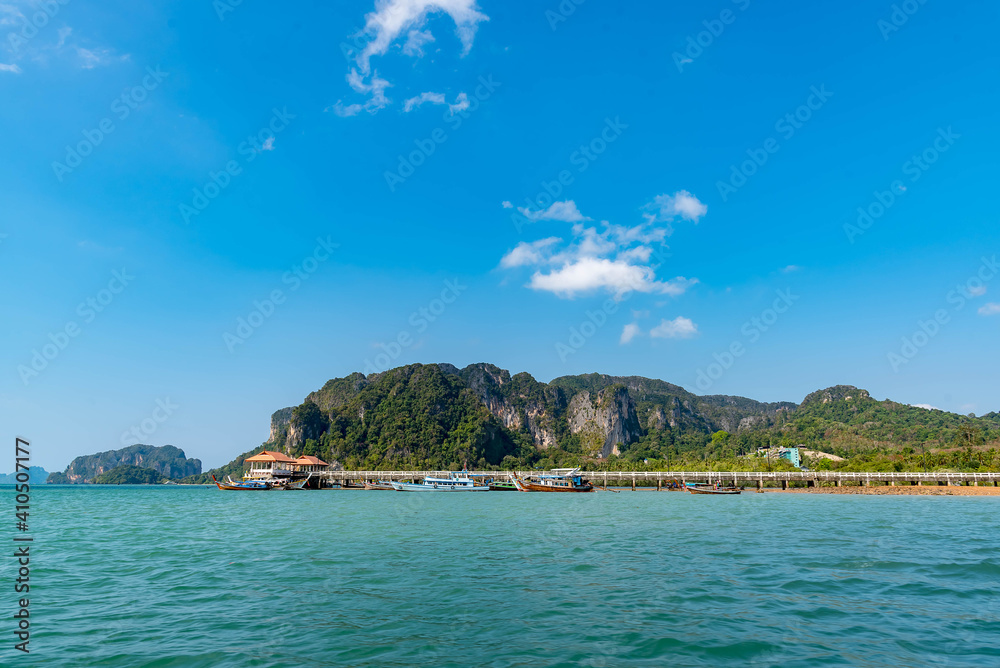 Fototapeta premium Vintage and retro toning of tropical beach with blue sky and clear sea which including of a wooden umbrella and chair in sunrise time with vintage retro tone. Vacation time as concept. 