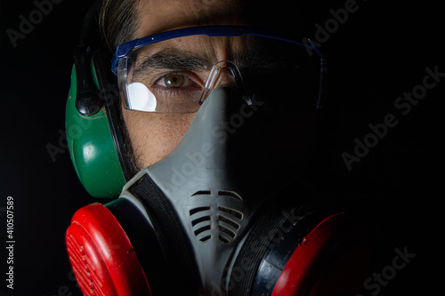 man working and wearing eye protectors, ear protectors and gas mask. on black background. Concept health virus coronavirus epidemic.