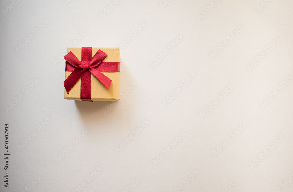 A small gift box with tied decorative bow and red ribbon