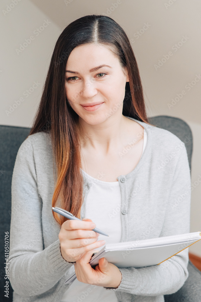Nice woman takes notes in a notebook. Learning from home. Nice woman takes notes in a notebook. Learning from home.