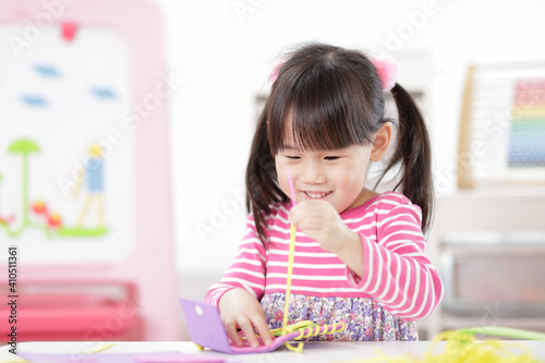 young girl sweing pad craft using plastic needle and yarn for homeschooling