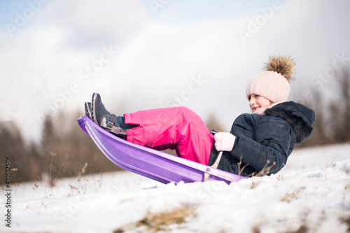 Little girl enjoying a sleigh ride. Child sledding. 