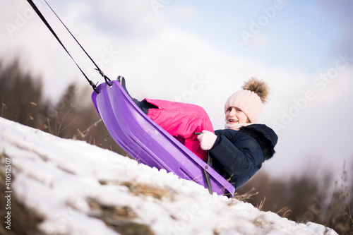 Little girl enjoying a sleigh ride. Child sledding. 