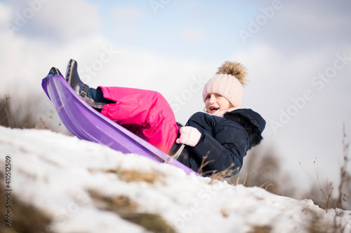 Little girl enjoying a sleigh ride. Child sledding. 
