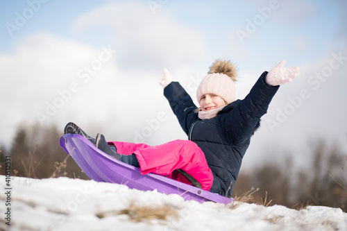 Little girl enjoying a sleigh ride. Child sledding. 