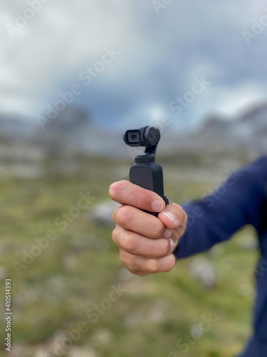 Fuente De, Spain - August 31, 2020: Young man at Picos de Europa National Park vlogging for youtube using the DJI Osmo Pocket gimbal camera.