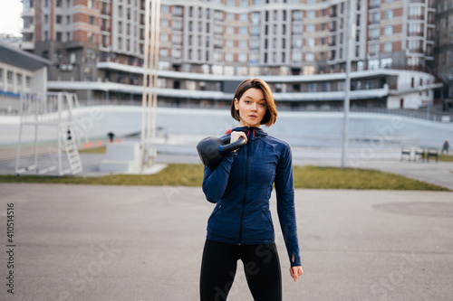 Young woman exercising with a kettlebell outside at stadium © teksomolika