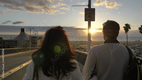 Santa Monica Pier blured people in background couple walking in slow motion camera forward epic sunset time