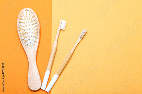 zero waste concept with bathroom accessories on yellow paper background. wooden hairbrush and two bamboo toothbrushes