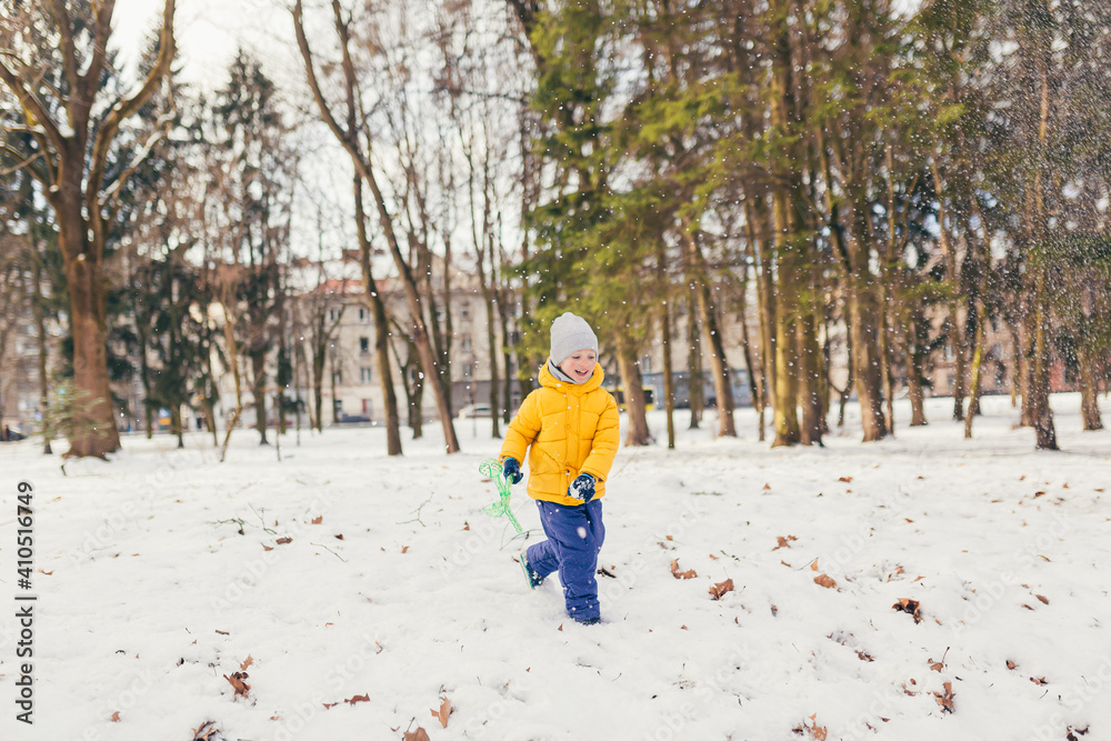 Little boy in a walk in the park with his family in winter, having fun and enjoying the snow Little boy in a walk in the park with his family in winter, having fun and enjoying the snow