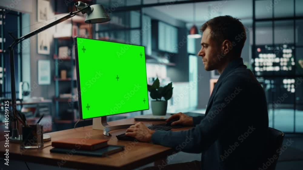 Handsome Caucasian Specialist Working on Desktop Computer with Green Screen Mock Up Display at Home Living Room. Freelance Man Chatting to Clients Over the Internet on Social Networks.