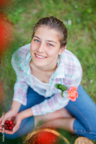 Pretty young girl picking cherry in garden