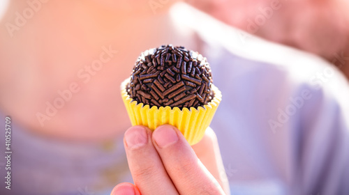 child's hand holding Brigadeiro, traditional Brazilian delicacy made with condensed milk, cocoa powder, butter and chocolate granules photo