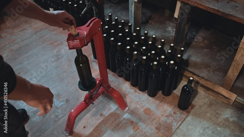 High angle view of the middle aged male winemaker standing near the special equipment and closed wine bottles with corks at the factory. Man at his workplace. Wine production step by step concept photo