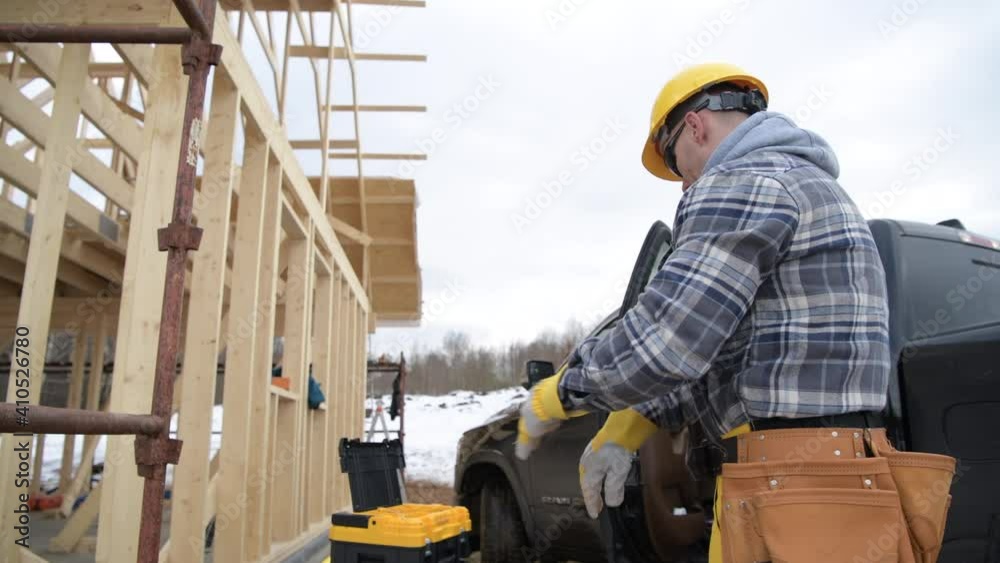 Construction Worker Wearing Safety Working Gloves in Front of Newly Constructed House Construction Worker Wearing Safety Working Gloves in Front of Newly Constructed House