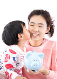 The lovely little girl is kissing the young mother with piggy bank