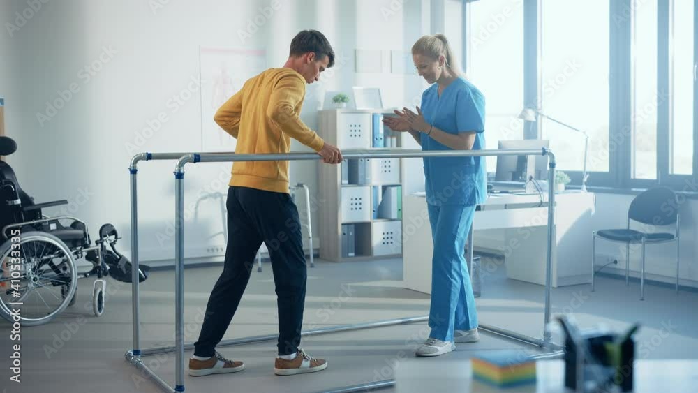 Hospital Physical Therapy Room: Strong Patient with Injury Walking Holding for Parallel Bars, Physiotherapist Encourages Assists, Helps Disabled Person Do Rehabilitative Physiotherapy. Slow Motion