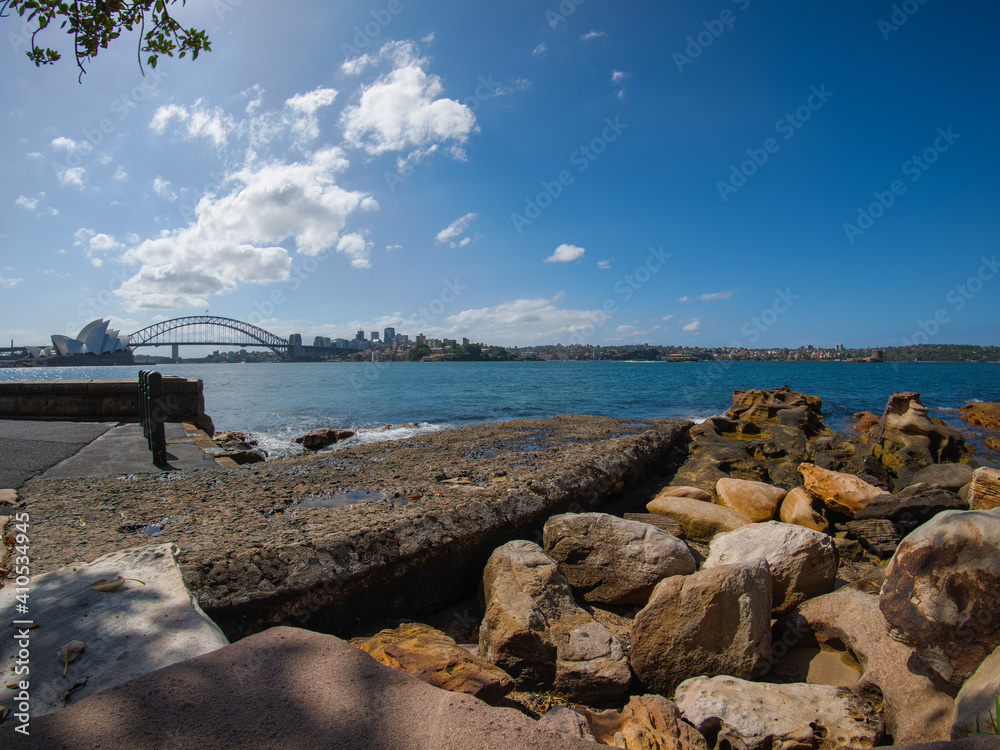 Panorama view of Sydney Harbour bridge beautiful blue partly cloudy skies botanical gardens and Sydney CBD high rise  apartment and office commercial buildings in background 