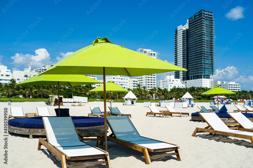 Miami Beach cityscape with colorful umbrellas and recliners along the shoreline