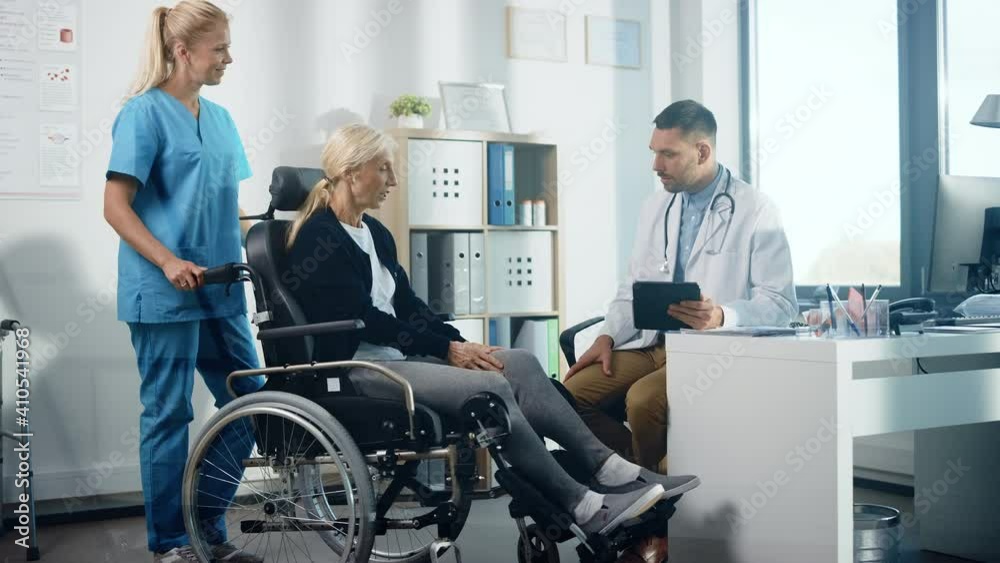 Hospital Physical Therapy: Strong Senior Female in Wheelchair, Talks to a Friendly Rehabilitation Physiotherapist Doctors Gives Advice, Plans Rehabilitation Treatment for Determined Disabled Patient Hospital Physical Therapy: Strong Senior Female in Wheelchair, Talks to a Friendly Rehabilitation Physiotherapist Doctors Gives Advice, Plans Rehabilitation Treatment for Determined Disabled Patient