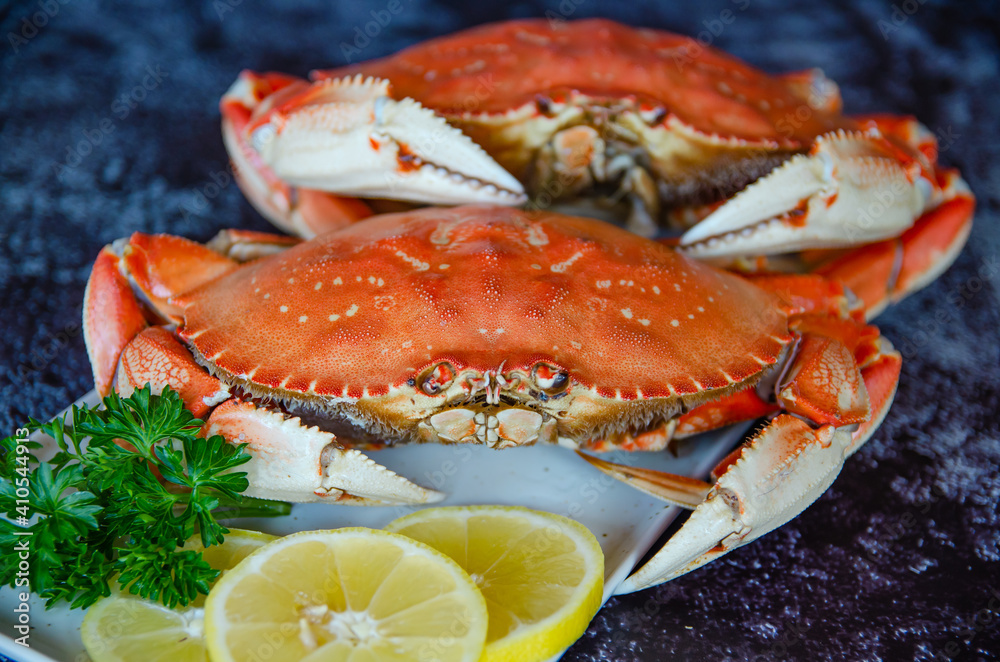 Two boiled crabs with lemon and parsley on a white plate Two boiled crabs with lemon and parsley on a white plate