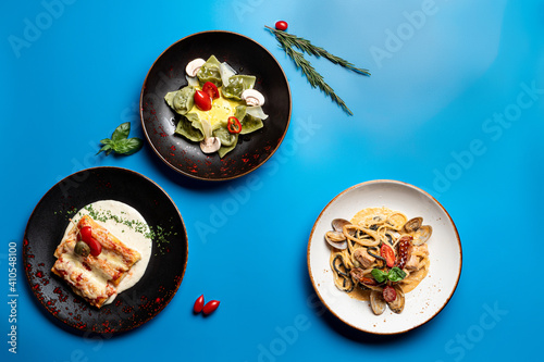 Directly above view of assortment of italian meals on bright background: pasta, ravioli and lasagna