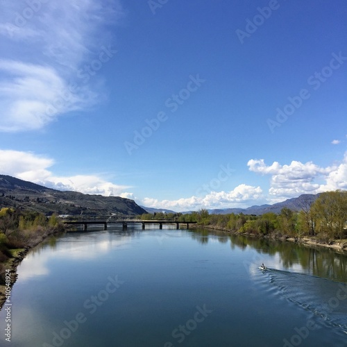 Bridge cross the North Thompson River, in Kamloops, British Columbia, Canada.  Beautiful reflection of the clouds, sky, and mountain in the river. © christopher