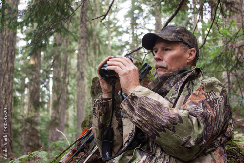 Bowhunter searching for elk with binoculars