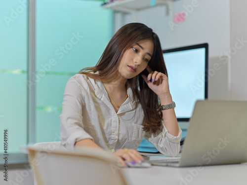 Portrait of female office worker work from home with laptop and computer