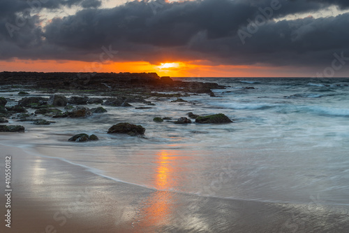 Grey clouds and rocky foreground overcast sunrise at the beach photo