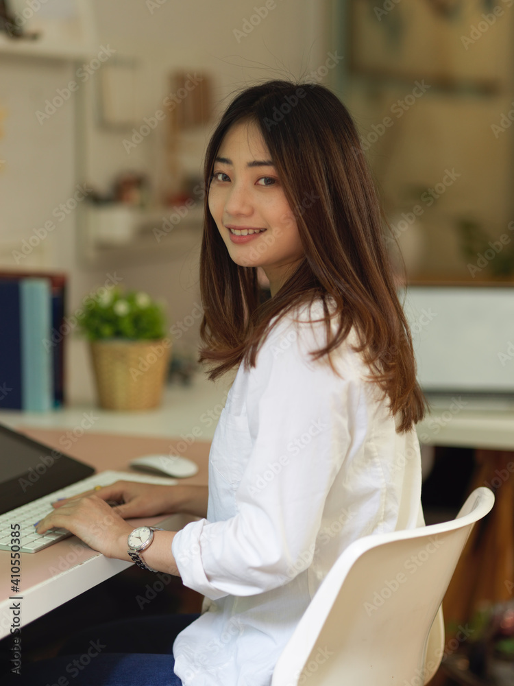 Female office worker smiling to camera while sitting at workplace