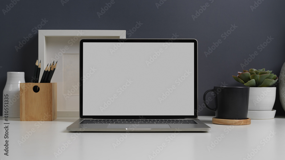 Workspace with laptop, stationery and decorations in home office room Workspace with laptop, stationery and decorations in home office room