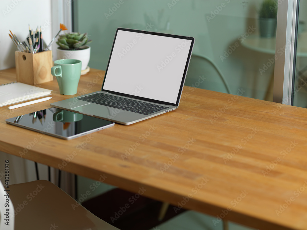 Workspace with laptop, tablet, supplies and copy space on wooden table Workspace with laptop, tablet, supplies and copy space on wooden table