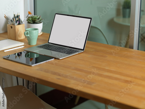 Workspace with laptop, tablet, supplies and copy space on wooden table