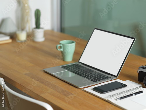 Worktable with laptop, smartphone, camera, and stationery in home office room