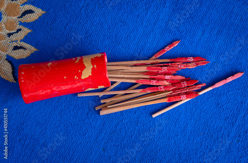 Bamboo cylinder with fortune sticks or Esiimsi falling on the floor before someone shaking it. In Chinese society, fortune telling is a respected and important part of social and business culture. photo