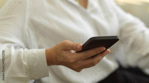 Female hand holding smartphone in office room