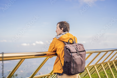 Young man tourist at Famous tourist attraction - Golden bridge at the top of the Ba Na Hills, Vietnam photo