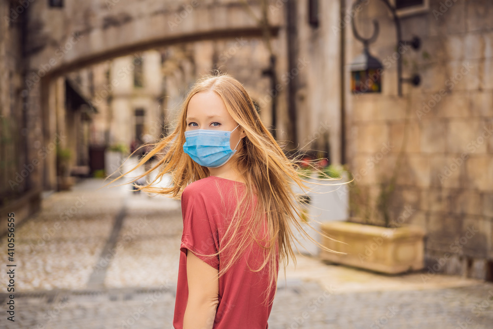 Young woman wearing a medical mask during COVID-19 coronavirus tourist walks down the street in a European city after the end of COVID-19 coronavirus. quarantine Young woman wearing a medical mask during COVID-19 coronavirus tourist walks down the street in a European city after the end of COVID-19 coronavirus. quarantine