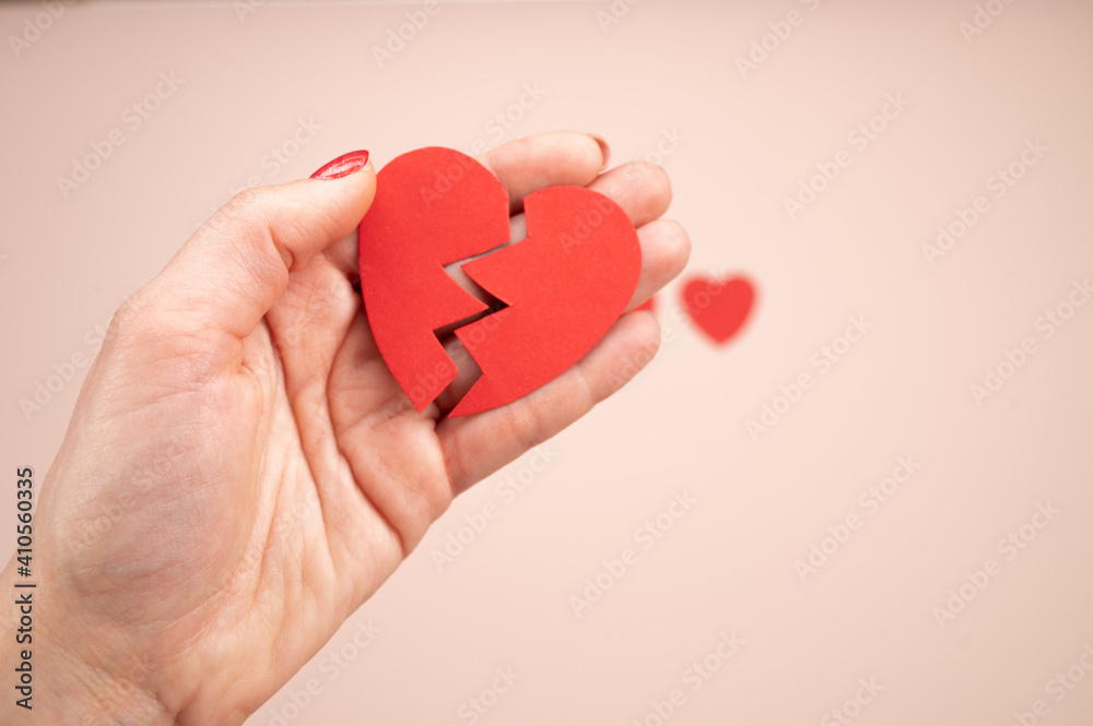 Woman hand holding broken paper red heart on pink background. Love, Wedding and Valentines day. Concept of disappointment, parting, separation Woman hand holding broken paper red heart on pink background. Love, Wedding and Valentines day. Concept of disappointment, parting, separation