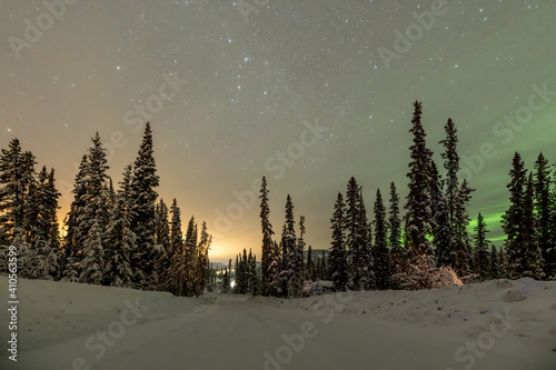 Night time view of an isolated road in northern Canada, Yukon Territory with some aurora borealis, northern lights, widlerness woods. 