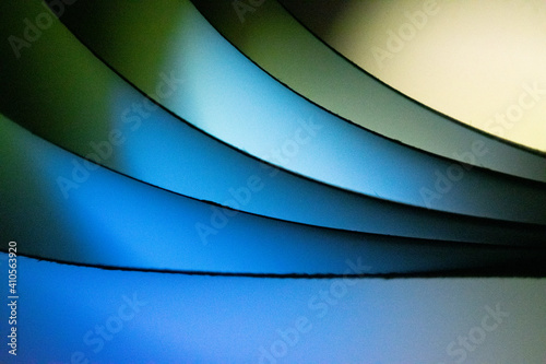 Background macro image pattern made of folded curved sheets of paper with multi color light illuminate  
