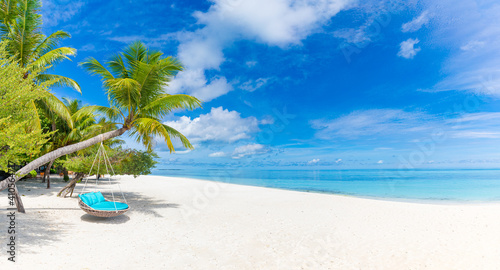 Tropical beach background as summer relax landscape with beach swing or hammock and white sand and calm sea for beach template. Amazing beach scene vacation and summer holiday concept. Luxury travel