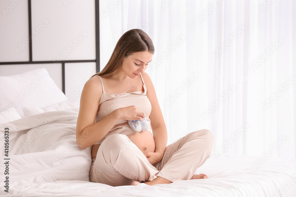 Beautiful pregnant woman with baby shoes at home Beautiful pregnant woman with baby shoes at home