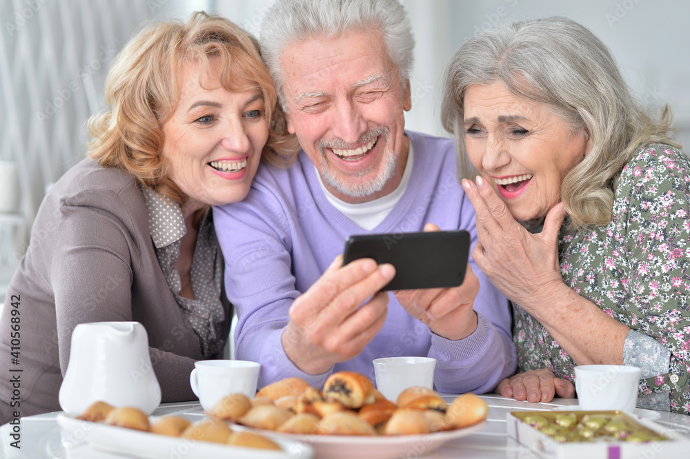 senior people with smartphone drinking tea