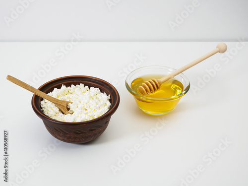 Diet breakfast cottage cheese with honey. Natural flower honey with honey dipper. Farm cottage cheese in handmade earthenware bowl on white background